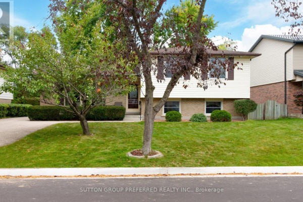 Exterior of the house with green lawn, trees, and sidewalk in the foreground. - 573 Jamaica Court, London South