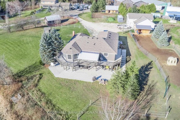 Rear view of a large residential home with a wrap-around deck overlooking a grassy yard. - 5735 Concession Rd 6, Adjala Tosorontio