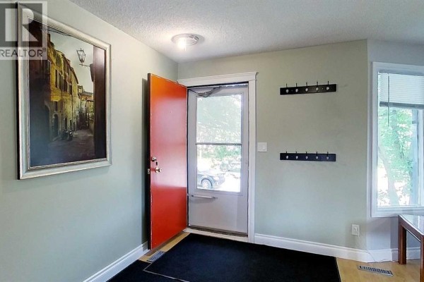 Entryway with light green walls, a red front door, and coat hooks on the wall. - 5735 Westhaven Drive, Edson