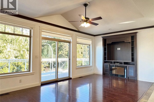Living room with dark wood floors, a vaulted ceiling, a ceiling fan, and a built-in entertainment center. - 5739 Bradbury Rd, Nanaimo