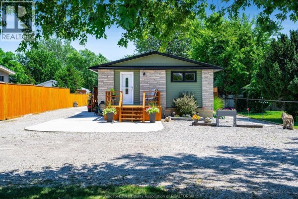 Front exterior of a small residential home with a stone and green siding and a wooden deck. - 574 Bevel Line, Leamington