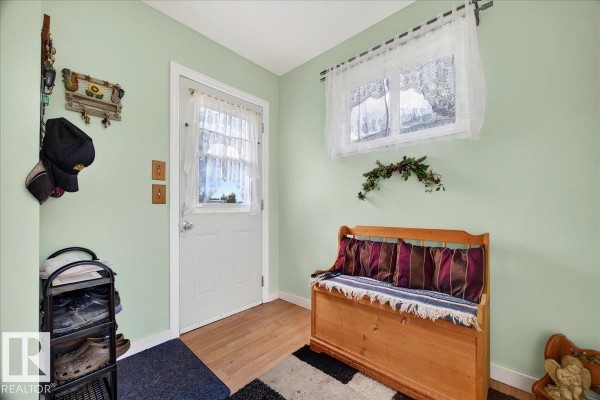 Mudroom with light green walls, a wooden bench with striped cushions, and a shoe rack near the door. - 57414 Rge Rd 222, Rural Sturgeon County