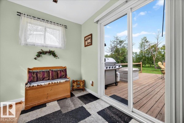 Interior view of a room with light green walls and a sliding glass door opening onto a wooden deck with a grill visible. - 57414 Rge Rd 222, Rural Sturgeon County