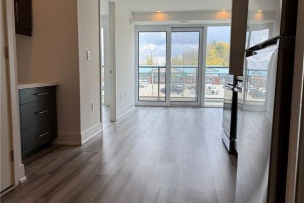 View from balcony of a suburban street with shops, cars, and a parking lot. - 575 Conklin Road Unit# 219, Brantford