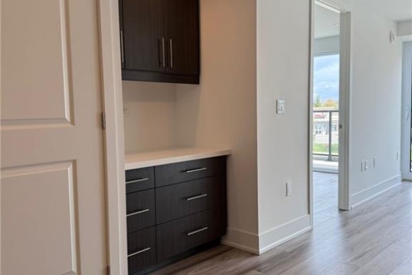 Room corner with grey wood-look flooring and a large window with a view of a street. - 575 Conklin Road Unit# 219, Brantford