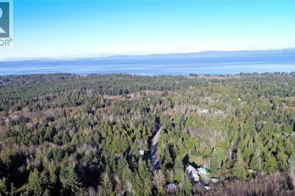 Aerial view of wooded area with ocean view and visible residential properties. - 575 Horne Lake Rd, Qualicum Beach