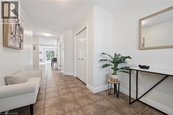 Spacious hallway with tiled floor, white bench, and double closet doors. - 575 Violet Street, Waterloo