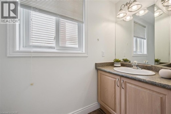 Powder room with vanity, sink, faucet, mirror, and window with blinds. - 575 Violet Street, Waterloo