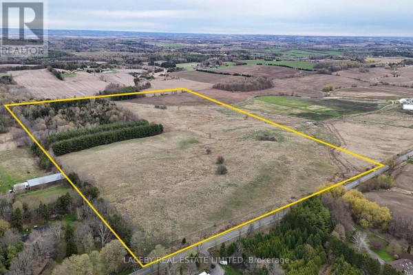 Aerial view of farmland with a road, buildings, and fields under a bright sky. - 5750 Third Line, New Tecumseth