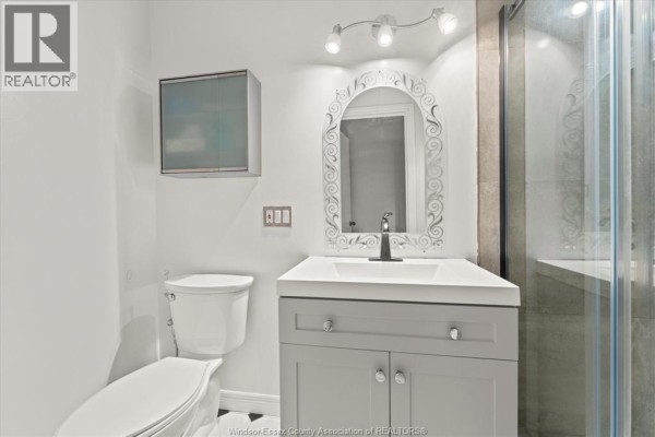 Modern bathroom with white vanity, mirror, and glass shower enclosure - 5753 Bishop Street, Lasalle