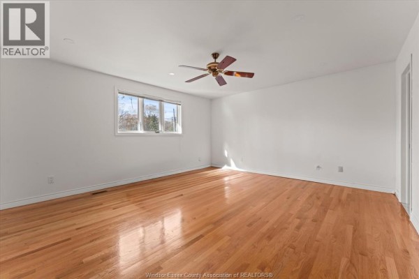 Spacious living room with hardwood floor, ceiling fan, and bright windows - 5753 Bishop Street, Lasalle