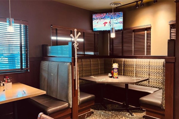 Close-up of booth seating in the restaurant, with a television screen showing a hockey game. - 5753 Hwy 9 Highway, St Andrews