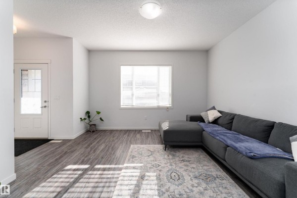 Living room with L-shaped sofa, patterned rug, and view of the entryway. - 577 Ebbers Wy Nw, Edmonton