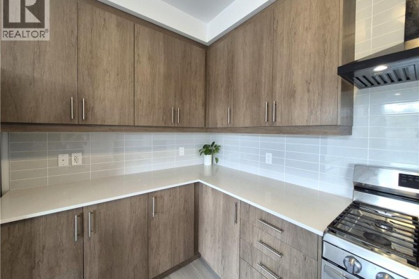Corner view of a kitchen featuring light grey subway tile backsplash, white countertops, and wood cabinets. - 578 Telfer Street, Woodstock