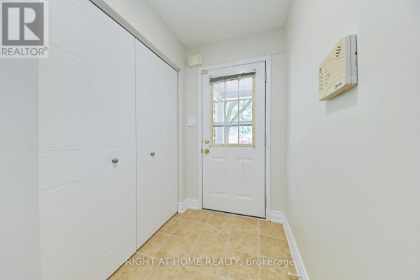 Interior hallway with beige tiled floor, white walls, white bi-fold doors, and a glass-paneled door to the outside. - 58 - 1055 Gordon Street, Guelph