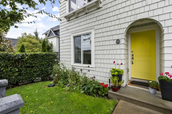 Close-up of a townhouse entrance with a bright yellow door and white shingle siding. - 58 16678 25 Avenue, Surrey