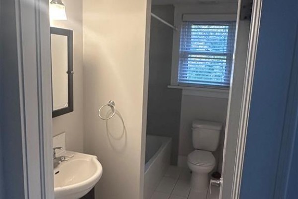 Small bathroom with white sink, mirror, toilet, and bathtub with blinds on the window. - 58-60 Madison Avenue N Unit# 203, Kitchener