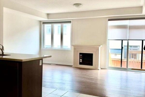 Living room with a white fireplace, hardwood floors, and large windows overlooking a deck. - 58 Boiton Street, Richmond Hill