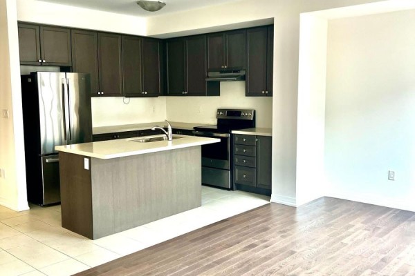 Kitchen with dark wood cabinets, stainless steel appliances, and a light stone island. - 58 Boiton Street, Richmond Hill