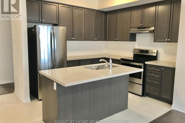 Kitchen with dark gray cabinets, stainless steel appliances, and a light stone island counter. - 58 Boiton Street, Richmond Hill