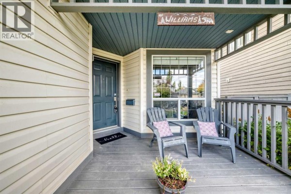 Covered front porch with two grey chairs, a dark blue door, and a welcome mat. - 58 Chaparral Terrace Se, Calgary