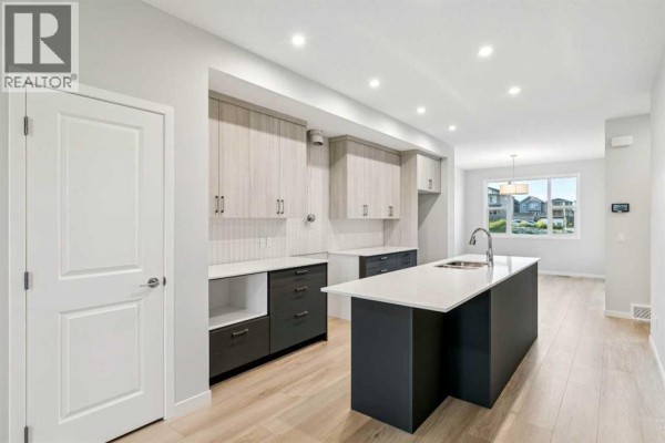 Modern kitchen with white countertops, two-tone cabinets, and island with sink. - 58 Creekview Avenue, Calgary