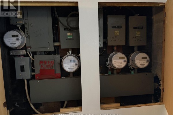 Close-up of electrical panels and meters mounted on a wooden wall. - 58 Forty-first Street, Toronto