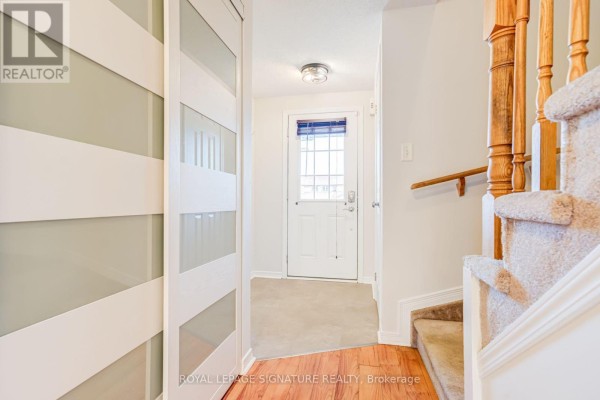 Interior hallway of a townhouse with a closet, carpeted stairs and a front door. - 58 Goodwin Drive, Barrie