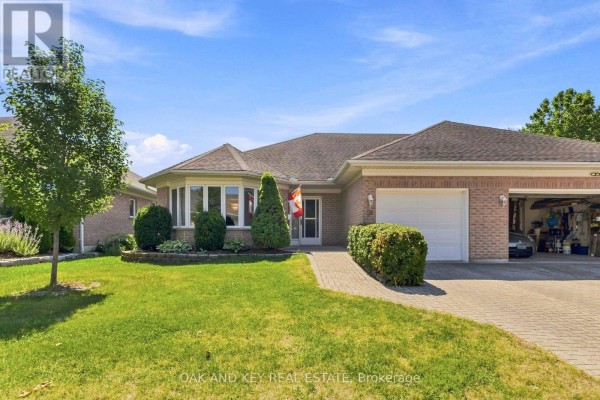 Front view of a brick bungalow with a garage door, walkway, and lush green lawn. - 58 Ilderbrook Circle, Middlesex Centre
