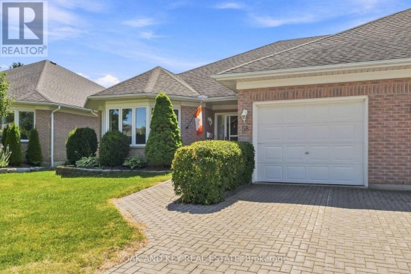 Close-up of the brick bungalow's front entrance, showing a garage door and paved driveway. - 58 Ilderbrook Circle, Middlesex Centre