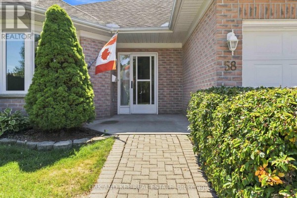 Close-up of the front entrance with a Canadian flag, paved walkway, and brick exterior. - 58 Ilderbrook Circle, Middlesex Centre