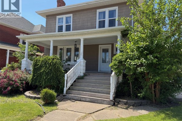 Back view of a house with stone facade, balcony, and wooden deck stairs. - 58 Margaret Avenue, Wallaceburg