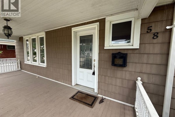 Backyard with green grass, a wooden deck, chairs, and a view of a wide canal. - 58 Margaret Avenue, Wallaceburg