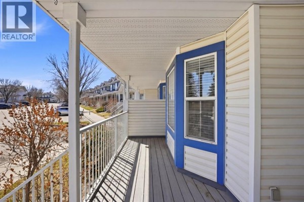 View from a covered townhouse balcony with white railings and beige siding. - 58 Martin Crossing Court Ne, Calgary