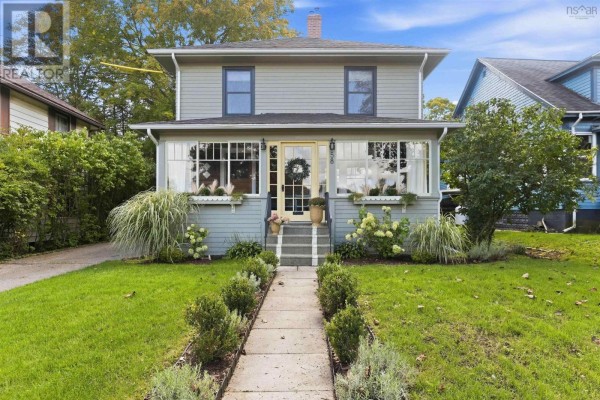 A light green house with a yellow front door and a concrete walkway. - 58 Park Street, Kentville