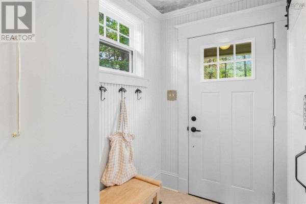 Interior entryway with a white door, window, beadboard walls, bench, and hooks. - 58 Park Street, Kentville