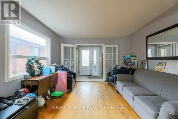 Living room with hardwood floors, a grey sofa, and double doors leading to the entrance. - 58 Park Street, Toronto