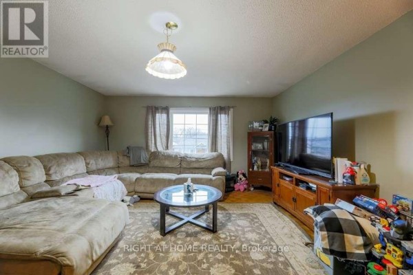 Family room with a large sectional sofa, television, and a coffee table on a rug. - 58 Park Street, Toronto