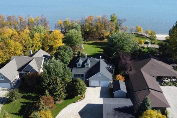 Aerial view of houses and yards in a lakeside community with vibrant autumn foliage and a large body of water. - 58 Royal Road, Gimli