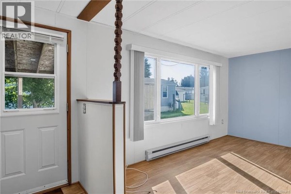 Interior view of a living room with white walls, large windows, and wood laminate flooring. - 58 Second Street, Sussex Corner
