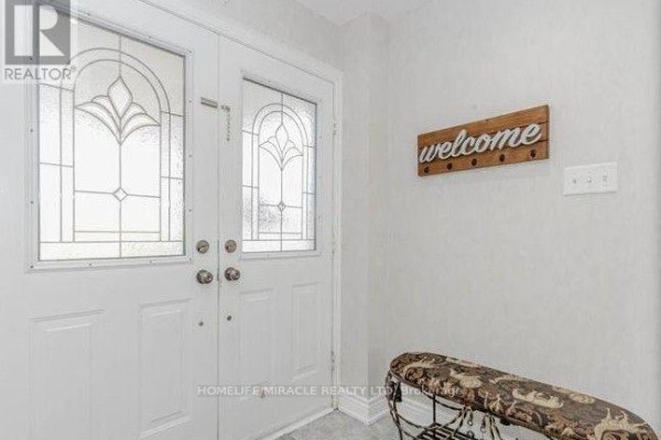 Interior view of double white front doors with glass and a wooden welcome sign. - 58 Summerdale Crescent, Brampton