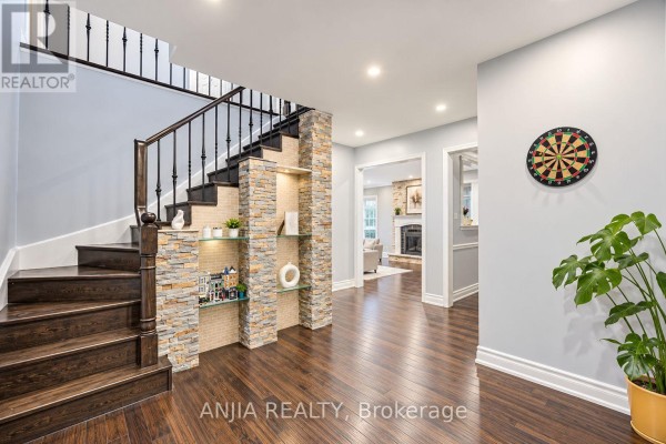 Interior foyer with dark wood flooring, a staircase with dark wood railings, and decorative stone feature wall. - 58 Summerfeldt Crescent, Markham