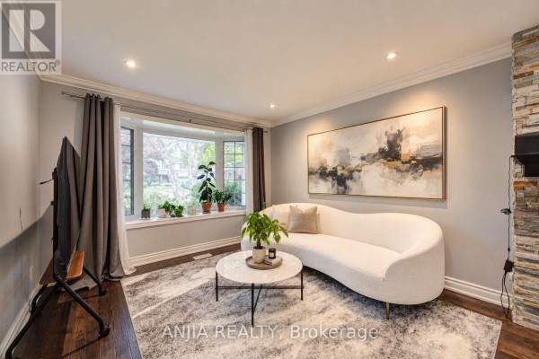 Living room with a bay window, white curved sofa, grey rug, and large abstract wall art. - 58 Summerfeldt Crescent, Markham