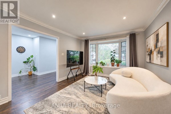 Living room with a bay window, white curved sofa, grey rug, and a view into the foyer. - 58 Summerfeldt Crescent, Markham