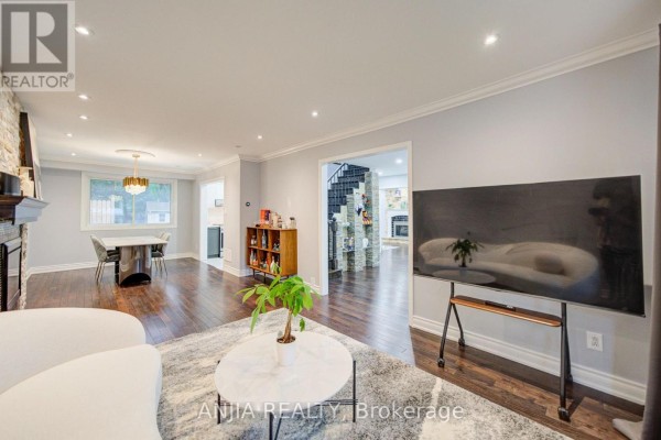 Open concept living and dining area with dark wood floors, a large television, and a view to the foyer and staircase. - 58 Summerfeldt Crescent, Markham