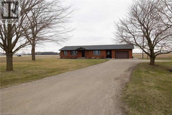 Front view of a brick bungalow with a garage, driveway, and mature trees. - 58 Tenth Concession Road, Burford
