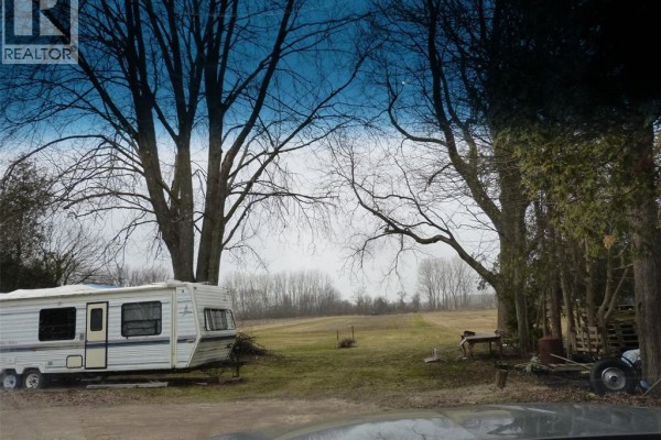 Another angle of open field with trailer and trees, showing rural landscape - 581 Highway 77, Leamington