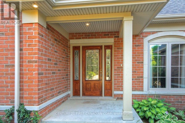 Close-up of the wooden front door with glass panels, surrounded by brick. - 581 Plane Tree Drive, London North