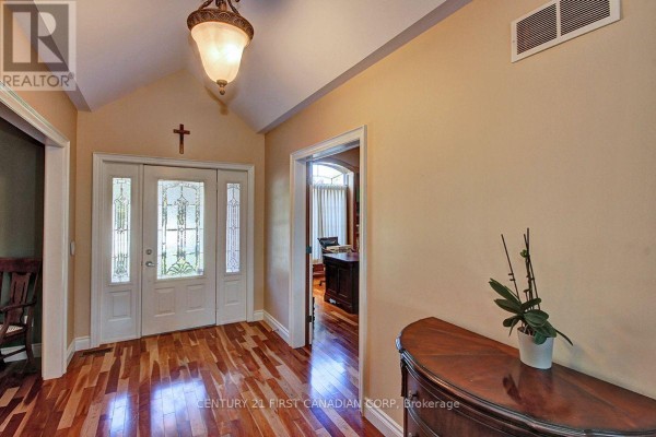 Foyer with hardwood floors, a decorative chandelier, and a view into a home office. - 581 Plane Tree Drive, London North