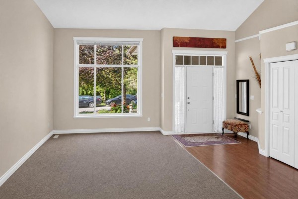 View of living room with beige walls, large window, and architectural columns. - 5818 167a Street, Surrey